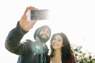 Junges glückliches Paar macht ein Selfie im Gegenlicht - JRFF000403