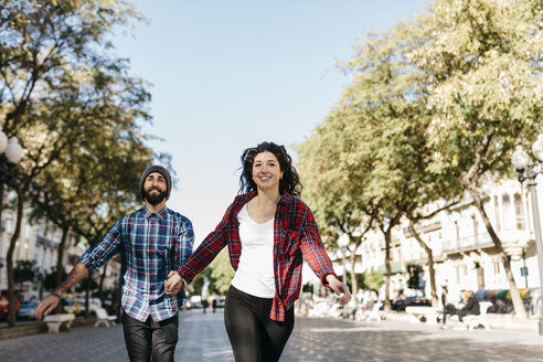 Spain, Tarragona, happy young couple running in the city - JRFF000413