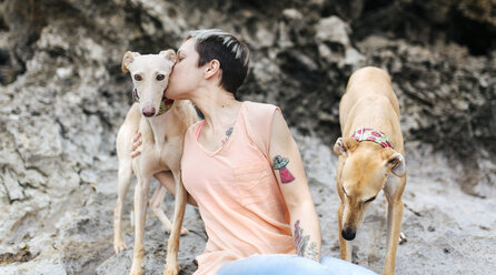 Spain, Llanes, young woman with her greyhounds on the beach - MGOF001376