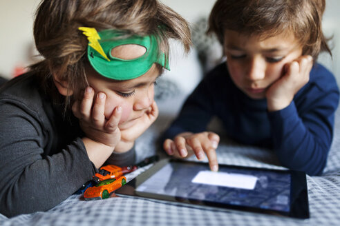 Zwei kleine Jungen liegen auf dem Bett und spielen mit einem digitalen Tablet - VABF000137