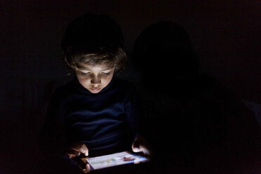 Little boy in darkness playing with digital tablet - VABF000139