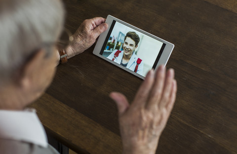 Senior man using mini tablet for skyping with his grandson stock photo