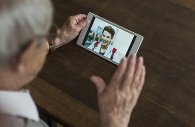 Senior man using mini tablet for skyping with his grandson - UUF006570