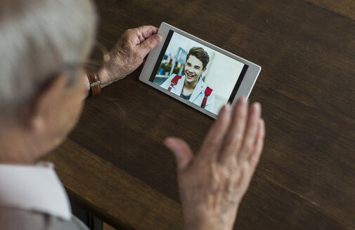 Ein älterer Mann benutzt ein Mini-Tablet, um mit seinem Enkel zu skypen - UUF006570