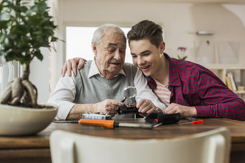 Porträt eines älteren Mannes und seines Enkels mit Spielzeugeisenbahn zu Hause - UUF006581