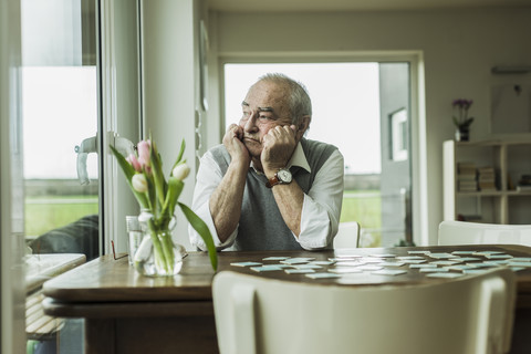 Porträt eines traurigen älteren Mannes, der durch ein Fenster schaut, lizenzfreies Stockfoto