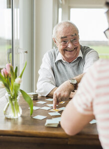 Porträt eines lachenden älteren Mannes, der mit seinem Enkel Memory spielt - UUF006596