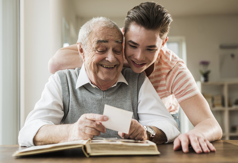 Grandfather and grandson watching old photographies together stock photo