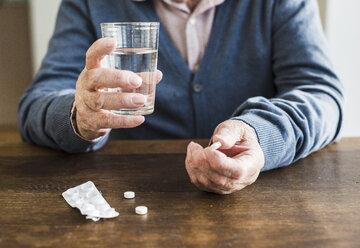 Hands of senior man holding tablet and glass of water, close-up - UUF006616