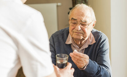 Älterer Mann erhält Tablette und Glas Wasser - UUF006619