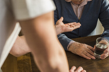 Hand of young man giving senior man his tablet - UUF006620