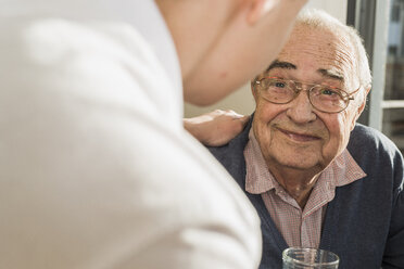 Porträt eines lächelnden älteren Mannes von Angesicht zu Angesicht mit seiner Altenpflegerin - UUF006622