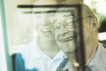 Porträt eines älteren Mannes und seines Enkels im Hintergrund, der durch ein Fenster schaut - UUF006624