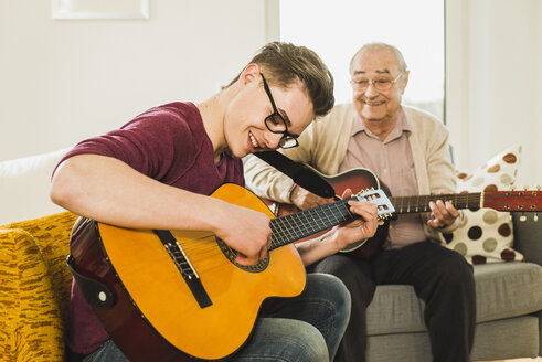 Großvater und Enkel spielen zusammen Gitarre - UUF006630