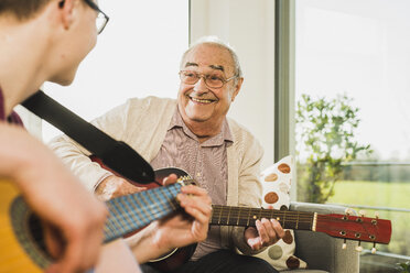 Portrait of senior man playing guitar with his grandson - UUF006631