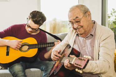 Portrait of senior man playing guitar with his grandson - UUF006632