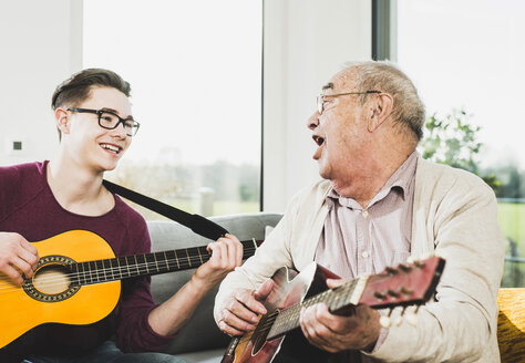 Älterer Mann singt und spielt Gitarre mit seinem Enkel - UUF006634