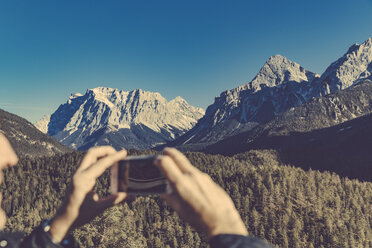 Hände, die ein Smartphone-Foto von Zugspitze und Zugspitzplatt von Biberwier, Tirol, Österreich aus aufnehmen - MFF002627