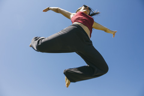 Springende Frau vor blauem Himmel, lizenzfreies Stockfoto