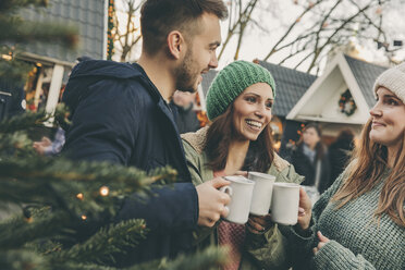 Drei Freunde trinken einen heißen Punsch auf dem Weihnachtsmarkt - MFF002653