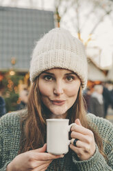 Eine Frau trinkt einen heißen Punsch auf dem Weihnachtsmarkt - MFF002654