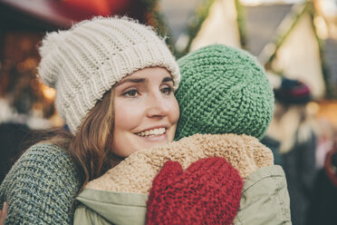 Glückliche Frau umarmt eine Freundin auf dem Weihnachtsmarkt - MFF002659