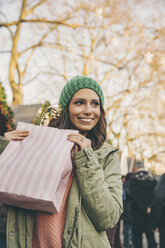 Glückliche Frau mit einer Geschenktüte auf dem Weihnachtsmarkt - MFF002660