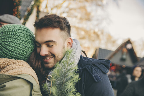 Mann und Frau umarmen sich auf dem Weihnachtsmarkt - MFF002663