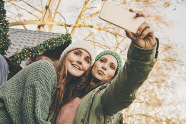 Zwei glückliche Frauen machen ein Selfie auf dem Weihnachtsmarkt - MFF002666