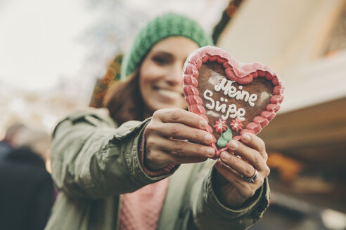 Woman holding up a gingerbread heart on the Christmas Market - MFF002669