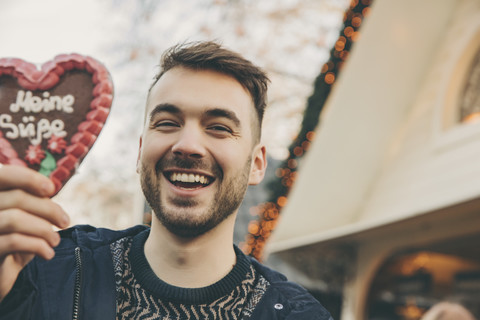 Portrait of man holding up a gingerbread heart on the Christmas Market stock photo