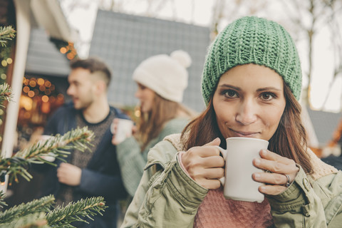 Eine Frau trinkt einen heißen Punsch auf dem Weihnachtsmarkt, lizenzfreies Stockfoto