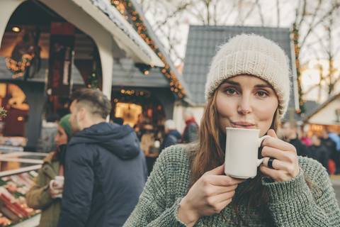 Eine Frau trinkt einen heißen Punsch auf dem Weihnachtsmarkt, lizenzfreies Stockfoto