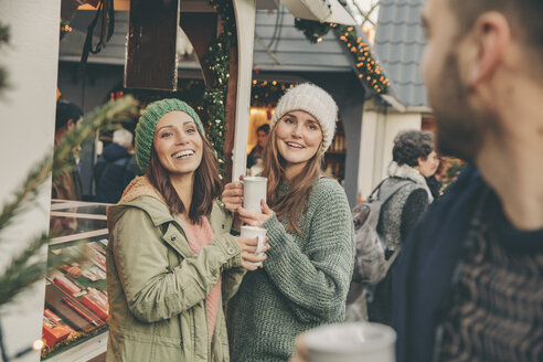 Glückliche Freunde bei einem heißen Punsch auf dem Weihnachtsmarkt - MFF002678