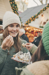 Zwei Frauen essen eine heiße Waffel auf dem Weihnachtsmarkt - MFF002680