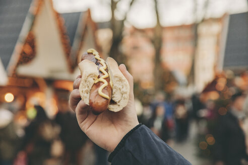 Hand eines Mannes, der eine Bratwurst auf dem Weihnachtsmarkt hält - MFF002681