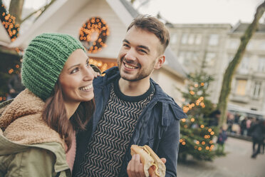 Happy couple having a snack on the Christmas Market - MFF002682