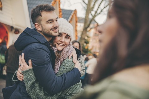 Mann und Frau umarmen sich auf dem Weihnachtsmarkt, lizenzfreies Stockfoto