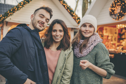 Porträt von drei Freunden auf dem Weihnachtsmarkt, lizenzfreies Stockfoto