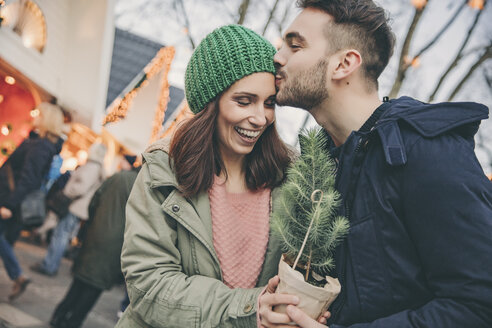 Man giving a small tree to a woman on the Christmas Market - MFF002688