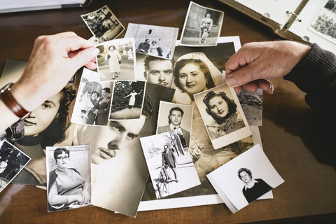 Ein älteres Ehepaar hält alte Fotos von sich in den Händen, lizenzfreies Stockfoto