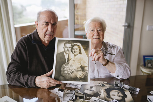 Senior couple showing their wedding photo at home - GEMF000721