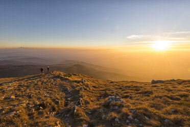 Italien, Marken, Monte San Vicino, zwei Wanderer betrachten die Aussicht bei Sonnenuntergang - LOMF000211