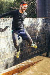 Teilnehmer eines extremen Hindernisrennens springt über eine Mauer - MGOF001379