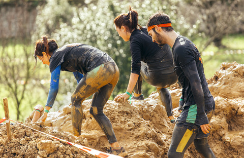 Participants in extreme obstacle race, running through mud stock photo