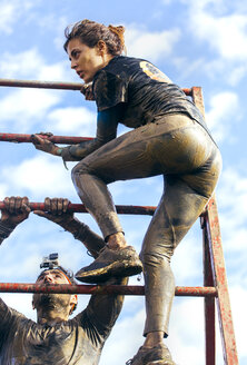 Participants in extreme obstacle race climbing over hurdle - MGOF001405