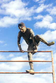 Participants in extreme obstacle race climbing over hurdle - MGOF001406