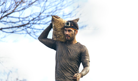 Teilnehmer eines extremen Hindernisrennens mit Sandsäcken, lizenzfreies Stockfoto