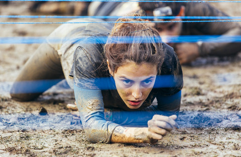 Participants in extreme obstacle race crawling under electric wire stock photo