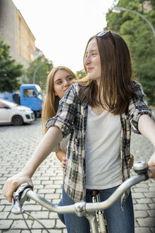 Zwei Mädchen im Teenageralter zusammen auf einem Fahrrad - OJF000109